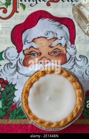 Tarte aux pommes de terre hachée glacée de Sainsburys sur une serviette de Noël festive - pâtisseries fourrées de viande hachée, recouvertes de glaçage blanc doux Banque D'Images