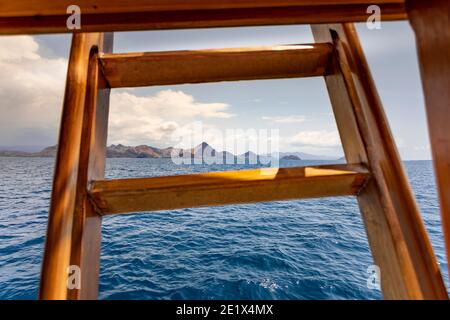 vue panoramique depuis un bateau de croisière en bois jusqu'à la turquoise L'eau et une étendue d'île à l'horizon à Komodo Parc marin national Banque D'Images