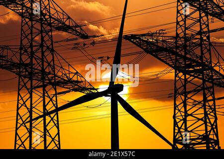 Deux pylônes de ligne aérienne et une éolienne devant le soleil, Witten, région de la Ruhr, Rhénanie-du-Nord-Westphalie, Allemagne Banque D'Images