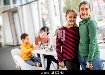 De jolies petites filles debout devant un groupe d'enfants programmation de jouets électriques et de robots dans les salles de classe de robotique Banque D'Images