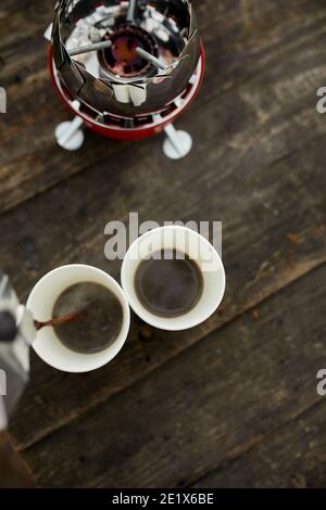 Voyageur homme qui verse du café chaud frais de la cafetière geyser dans une tasse à l'extérieur, étape par étape, activité de voyage pour se détendre, brousse, aventure, tra Banque D'Images