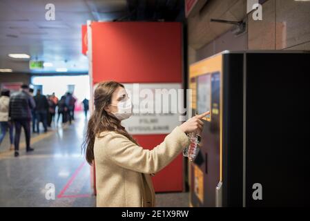 Belle fille portant masque médical de protection et vêtements à la mode utilise distributeur automatique pour l'argent.Nouveau concept normal pendant la pandémie corona, covid19.