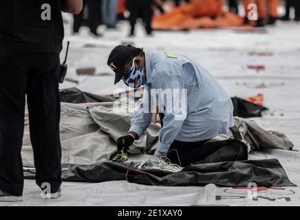 Jakarta, Indonésie. 10 janvier 2021. L'agent du Comité national de la sécurité des transports examine les débris récupérés sur le site de l'accident Sriwijaya Air SJ 182, à quai, au port de Tanjung Priok, à Jakarta, en Indonésie, le dimanche 10 janvier 2021. (Photo par Aditya Saputra/INA photo Agency/Sipa USA) crédit: SIPA USA/Alay Live News Banque D'Images