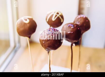 Les petites bouchées enrobées de chocolat sont également connues sous le nom de gâteaux. Petits gâteaux glacés sur bâton de bois. Mise au point sélective avec espace pour le texte sur fond blanc. Banque D'Images