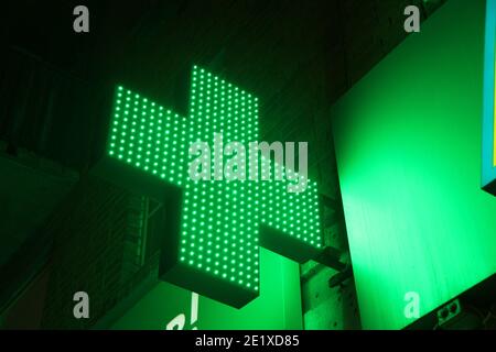 Croix de pixels lumineuse des lampes LED sur fond noir. Symbole de la croix verte de la santé, de la médecine, de l'auto-soins. Photo avec espace vide pour le texte et les des Banque D'Images