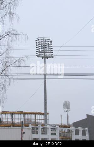 Projecteur de stade avec poteau métallique, mât d'éclairage, tour avec projecteurs dans le stade de sport contre le ciel blanc Banque D'Images