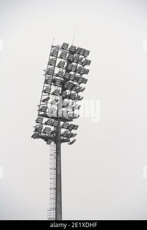 Projecteur de stade avec poteau métallique, mât d'éclairage, tour avec projecteurs dans le stade de sport contre le ciel blanc Banque D'Images