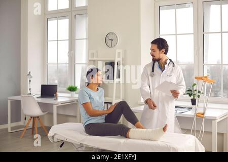 Chirurgien orthopédique interrogeant une femme avec une jambe cassée et lui donnant conseils de récupération Banque D'Images