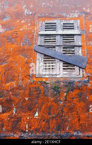 Le lichen orange abstrait et la mousse poussent sur l'ancien mur en pierre et la fenêtre en bois du temple de Wat Sampov, Cambodge. Banque D'Images