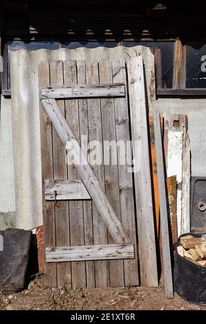 Ancienne porte en bois retirée sur le mur. Arrière-plan rétro et abîmé Banque D'Images