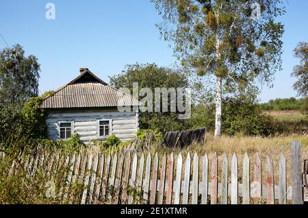 Maison abandonnée en campagne. Ancien bâtiment en bois avec clôture à l'automne Banque D'Images