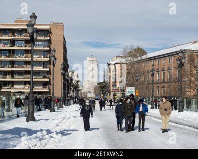 Madrid, Espagne. 10 janvier 2021. Les gens qui marchent dans la rue Bailen avec un gratte-ciel "Tour de Madrid" en arrière-plan, le lendemain de la tempête Filomena détesta Madrid. Après la tempête Filomena, Madrid (Espagne) est couverte de neige et de glace, beaucoup d'arbres sont tombés et il n'est pas possible d'utiliser la voiture dans la plupart des rues mais les gens marchent autour de la ville. © Valentin Sama-Rojo/Alamy Live News. Banque D'Images