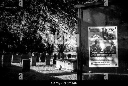 N.H.S. aide pendant l'auto-isolement affiche sur un panneau d'avis d'église avec cour de tombe. Banque D'Images