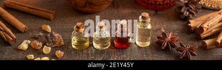 Affiche supérieure panoramique des bouteilles d'huile essentielle avec encens et Noël épices - anis étoilé et cannelle Banque D'Images