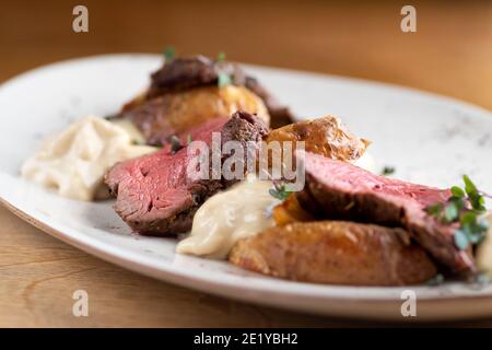 Filet de Mignon sur une assiette noire sur fond de légumes verts, d'épices et de légumes, sur une feuille de cuivre. Gros plan. Banque D'Images