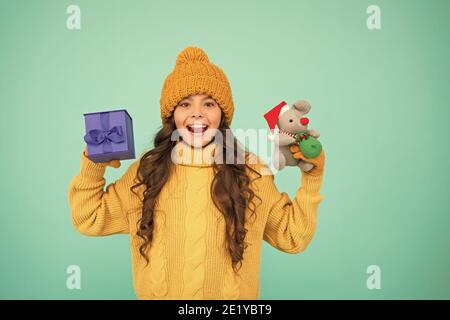 une petite fille tient le jouet de souris et la boîte de cadeau. enfant tricoté vêtements jouer avec le rat jouet. magasin de jouets pour les enfants. noël est ici. noël préféré vacances d'hiver. heureux nouvel an 2020. cadeau de jouet de père noël mignon. Banque D'Images