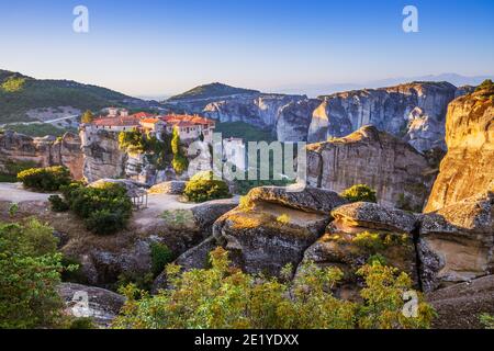 Meteora, Grèce. Formations rocheuses de grès et monastère Varlaam au lever du soleil. Banque D'Images