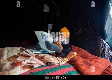 PORTRAIT D'UN MANIFESTANT D'AGRICULTEURS LISANT UN ARTICLE À LA FRONTIÈRE DE DELHI , ILS PROTESTENT CONTRE LA NOUVELLE LOI AGRICOLE ADOPTÉE PAR LE GOUVERNEMENT INDIEN. Banque D'Images