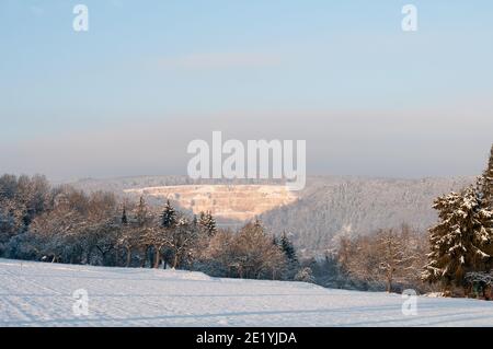 un paysage d'hiver dans l'alb souabe avec champ couvert de neige et une carrière de calcaire sur une colline boisée Banque D'Images