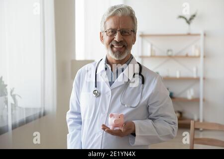 Portrait d'un médecin mûr souriant avec le dos de porc dans les mains. Banque D'Images
