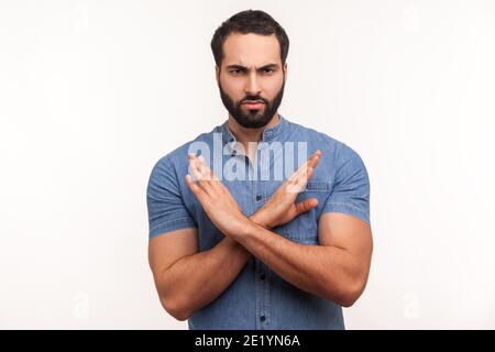 Il n'y a aucun moyen. Homme barbu avec une main très bosseuse en chemise bleue montrant x geste avec les mains, signe de rejet, avertissement sur la mauvaise voie. Studio d'intérieur tourné isol Banque D'Images