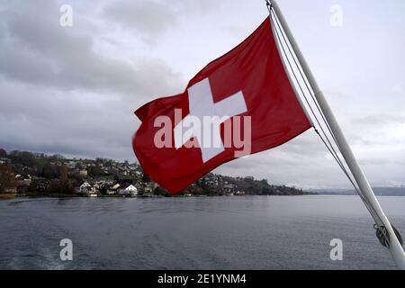 Drapeau fédéral suisse soufflant dans le vent au-dessus du lac de Zurich. Banque D'Images