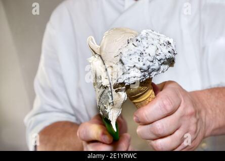 Les mains de la machine à glace en mettant la glace dans le cône de gaufres, la crème et les saveurs de stracciatella de chocolat Banque D'Images