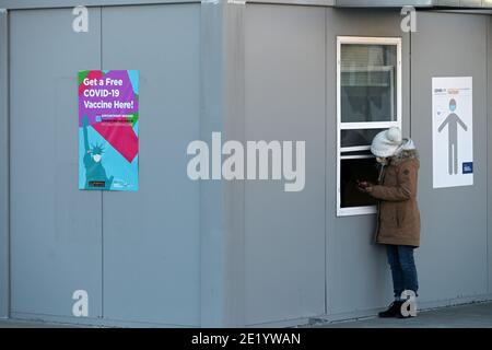 Une femme se tient à une fenêtre à l'intérieur du site de vaccination de l'hôpital NYCHealth situé à l'extérieur du terminal de l'armée de Brooklyn, dans le quartier de Brooklyn, New York, le 10 janvier 2021. Le 11 janvier, la ville de New York activera cinq points de vaccination prioritaires dans le groupe 1B, qui comprend les travailleurs de la santé, les travailleurs de l'éducation, les premiers intervenants, les travailleurs de la sécurité publique, les travailleurs des transports en commun et les quelque 1.4 millions de personnes âgées de 75 ans et plus. Le site DE LA CHAUVE-SOURIS sera équipé de 27 membres du personnel de vaccination dans le but de donner chacun 5 doses de vaccin COVID-19 par heure. (Photo par un Banque D'Images