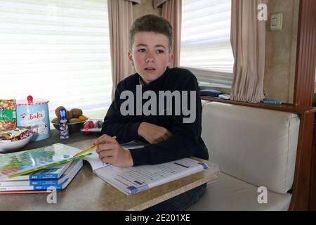 Royaume-Uni / Newport Pagnell / Pinders Circus / Boy faisant ses devoirs en caravane. Banque D'Images