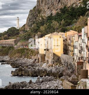 Vieilles maisons en pierre et phare sur la côte rocheuse de la ville de Cefalu dans la région de Palerme, Sicile, Italie. Banque D'Images