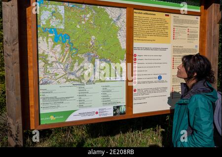 Femme asiatique randonnée dans le parc national de l'Eifel, dans le sud-ouest de l'Allemagne, lit le panneau d'information multilingue. Banque D'Images