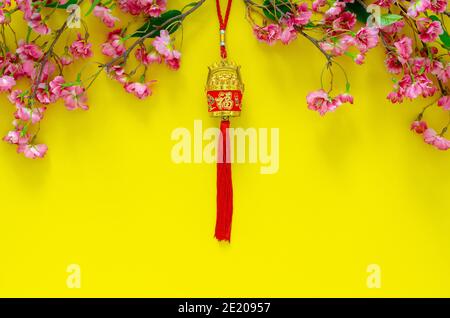 Pendentif suspendu pour ornement du nouvel an chinois (sens du mot est richesse) avec fleurs chinoises sur fond jaune. Banque D'Images