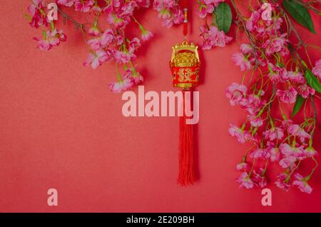 Pendentif suspendu pour ornement du nouvel an chinois (sens du mot est richesse) avec fleurs chinoises sur fond rouge. Banque D'Images