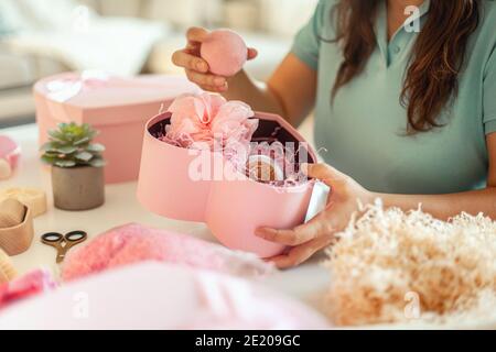 Femme préparant des boîtes-cadeaux en forme de coeur de couleur rose avec bio cosmétiques naturels de soins du corps Banque D'Images