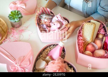 Femme préparant des boîtes-cadeaux en forme de coeur de couleur rose avec bio cosmétiques naturels de soins du corps Banque D'Images