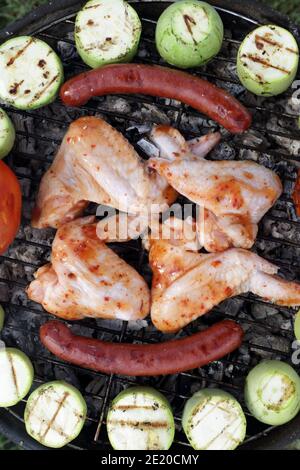 Ailes de poulet avec légumes sur la grille du gril lors du pique-nique Banque D'Images