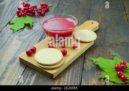 Confiture de Viburnum avec biscuits sur panneau de bois décoré de branches, feuilles. Composition d'automne. Concept de petit déjeuner Banque D'Images