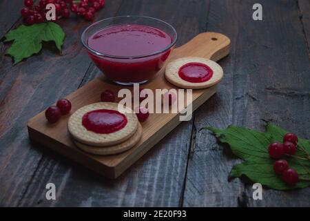 Confiture de Viburnum avec biscuits sur panneau de bois décoré de branches, feuilles. Composition d'automne. Concept de petit déjeuner Banque D'Images