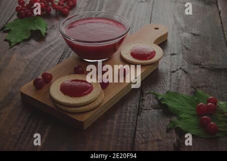 Confiture de Viburnum avec biscuits sur panneau de bois décoré de branches, feuilles. Composition d'automne. Concept de petit déjeuner Banque D'Images