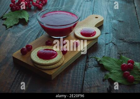 Confiture de Viburnum avec biscuits sur panneau de bois décoré de branches, feuilles. Composition d'automne. Concept de petit déjeuner Banque D'Images