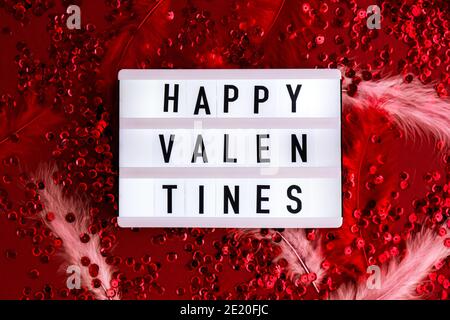 Visionneuse avec des mots pour des Saint-Valentin heureux sur fond rouge confetti orné de sequins avec des plumes. Saint Valentin arrière-plan de jour et de Noël Banque D'Images
