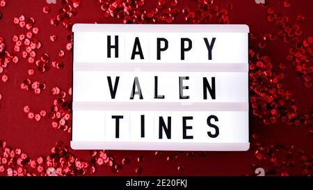 Visionneuse avec des mots pour des Saint-Valentin heureux sur fond rouge confetti orné de sequins avec des plumes. Saint Valentin arrière-plan de jour et de Noël Banque D'Images