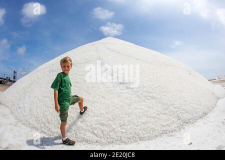 Un jeune garçon (MR) se tient à la base d'une masse de sel dans les salins de Pekelmeer, sur l'île Bonaire, dans les Caraïbes. Banque D'Images