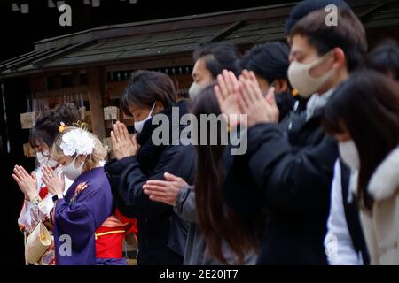 Tokyo, Japon. 11 janvier 2021. Les filles japonaises vêtues de kimonos colorés aux côtés de leurs parents prient au sanctuaire Meiji pendant le prochain jour de l'âge. Le jour de l'âge à venir (Seijin-no-Hi) est une fête pour féliciter et encourager tous ceux qui sont devenus adultes (20 ans) au Japon. La célébration annuelle a lieu le deuxième lundi de janvier, bien que de nombreux événements habituellement jubilants aient été annulés au sujet des craintes du coronavirus. Credit: Rodrigo Reyes Marin/ZUMA Wire/Alay Live News Banque D'Images