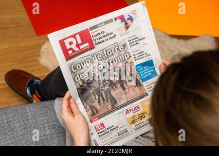 Paris, France - 7 janvier 2020: Une femme lisant le journal français le republicain Lorrain première page show storming of the U.S. Capitol par des partisans du président américain Donald Trump le 07 janvier 2021 Banque D'Images