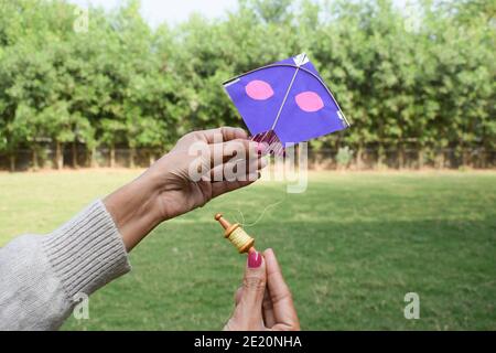 Femme, femme, fille volant d'un jouet miniature cerf-volant avec miniature mignon jouet spool manjha dans le parc. À l'occasion du festival de cerf-volant d'uttarayan, makars Banque D'Images