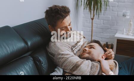 Un couple homosexuel heureux, récemment mariés, passe du temps ensemble, se câliner et se détendre sur le canapé. Photo de haute qualité Banque D'Images