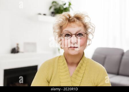 Smiling mature d'âge moyen grey haired woman looking at camera, heureux vieille dame en posant des lunettes à la maison à l'intérieur, à l'unique femme à la retraite senior positif Banque D'Images