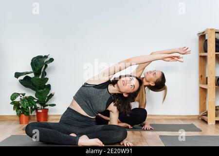 Femmes immergées pratiquant le yoga en se portant sur un côté tapis dans le club de santé Banque D'Images