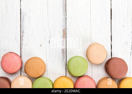 Bordure de pâte de macarons colorée sur table rustique vue en grand angle. Plat de couleur pastel français assortiment de bonbons carte de voeux avec copie sp Banque D'Images